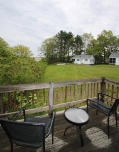 two chairs and a table on a deck with a field at Ogunquit Tides in Ogunquit