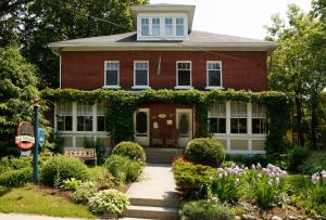 ein rotes Backsteinhaus mit Blumen davor in der Unterkunft Au Virage B&B in Magog-Orford