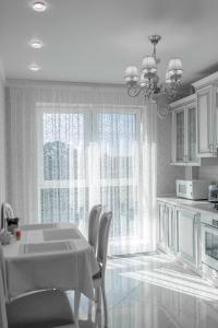 a white kitchen with a table and chairs and windows at Apartment Status in Kaliningrad