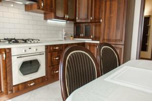 a kitchen with wooden cabinets and a table with chairs at Apartment Status in Kaliningrad