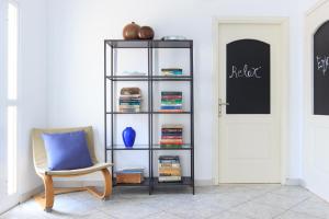 a room with a chair and a book shelf at Agora Apartment in Limenas