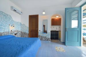 a bedroom with a blue bed and a kitchen at Azzurromare Residence in Procida