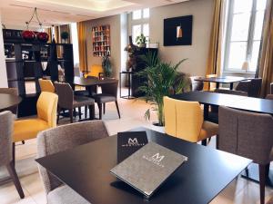 un restaurant avec des tables et des chaises et un livre sur une table dans l'établissement Domaine de Montjoie - Toulouse - BW Premier Collection, à Ramonville-Saint-Agne