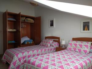 1 dormitorio con 2 camas con sábanas rosas y blancas en ApartamentosFinisterre, en Finisterre