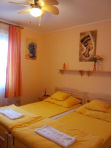 2 Einzelbetten in einem gelben Zimmer in der Unterkunft Tó- Party Panoráma Panzió & Wellness in Kiszombor