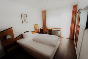 a bedroom with a white bed and a desk at Gästehaus am Kurpark in Villingen-Schwenningen