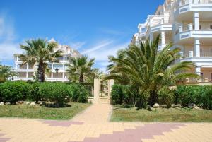 a large white building with palm trees in front of it at Las Dunas by HOMA in Isla del Moral