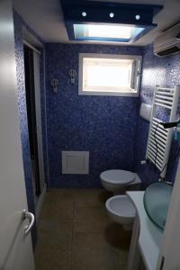 ポリニャーノ・ア・マーレにあるLa Dimora Della Contessa - Locazione Turisticaの青いバスルーム(トイレ2つ、窓付)