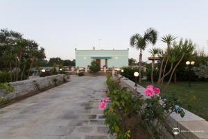 una passerella che conduce a un edificio con fiori rosa di B&B Le Due Cisterne a Vernole