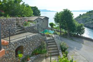 a set of stairs with a stone wall next to the water at Dora Apartment in Senj