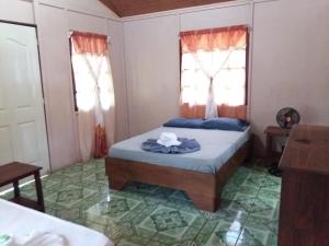 a bedroom with a bed and two windows at Cabaña en el Rincon Corcovado in Drake