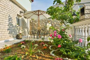 a patio with a table with an umbrella and flowers at Studio Apartman DORA in Senj
