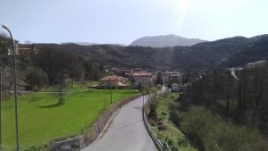 a winding road in a village with mountains in the background at Palia's Hotel in Laino Borgo