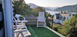 a balcony with white chairs and a view of the water at Berge & Laila's Private Apartment in Førde