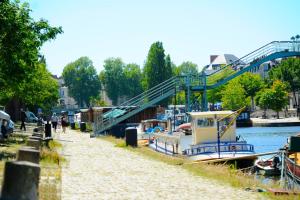 a boat is docked next to a river with a bridge at L'Erdream in Nantes