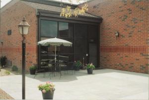 a patio with an umbrella and tables and chairs at Meadow Court Inn - Ithaca in Ithaca