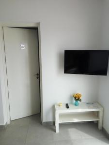 a room with a white wall with a tv and a table at Elenapa Holiday Apartments in Ayia Napa