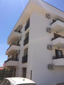 ein weißes Gebäude mit Balkonen und einem Auto, das vor der Tür geparkt ist in der Unterkunft Family Time Apartment Mamaia Nord in Mamaia Nord – Năvodari