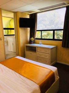 トゥーラ・デ・アジェンデにあるHotel Cuellarのベッドルーム1室(ベッド1台、ドレッサー、窓付)
