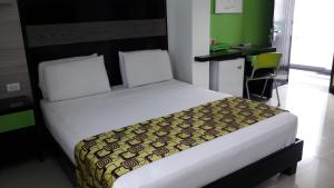 a bedroom with a large bed with a black and green headboard at Hotel Genova Prado in Barranquilla