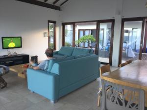un hombre sentado en un sofá azul en una sala de estar en Villa 06 - Taiba Beach Resort - TBR, en São Gonçalo do Amarante