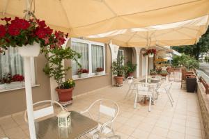 d'une terrasse avec des tables, des chaises et un parasol. dans l'établissement Atira Apart Hotel, à Olympiakí Aktí