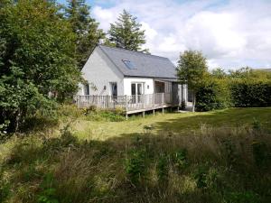 a white house with a porch in a field at Blossom Folly in Dunvegan