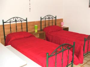 トリカーゼにあるCasa di Chiaraの赤いカバー付きのベッド2台が備わる客室です。