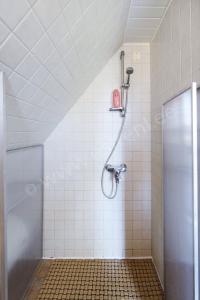 a shower in a white tiled bathroom with a shower stall at Kaju Guesthouses in Nasva
