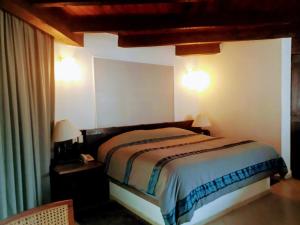 a bedroom with a bed and two lights on the wall at Hotel Del Parque in Tequisquiapan +26 photos
