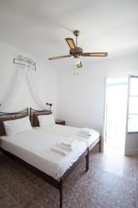 Helena's Apartments في Manganari: غرفة نوم مع سرير ومروحة سقف