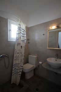 uma casa de banho com um WC, um lavatório e uma cortina de chuveiro em Helena's Apartments em Manganari