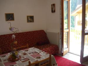 a living room with a red couch and a table at Appartamenti Mosconi Mistica in Vermiglio