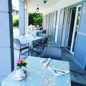 - deux tables et des chaises sur la terrasse couverte d'un restaurant dans l'établissement Foresteria Villa Margherita, à Colico