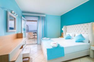 a bedroom with a bed with a blue wall at Sunny Hotel Thassos in Chrysi Ammoudia