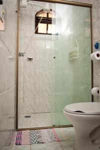 a bathroom with a glass shower with a toilet at Magnu´s Pousada in Paraty