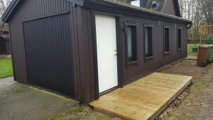 a brown shed with a white door and a wooden ramp at Cozy home in between Malmö & Lund in Åkarp