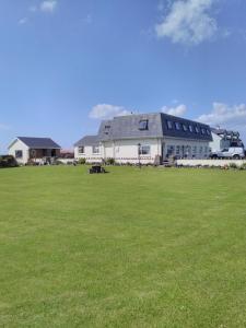 a large white building with a large grass field at Lahiff's Bay View Guest House in Spanish Point