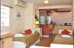Habitación pequeña con 2 camas y cocina en Temporary Rental Apartments en Córdoba