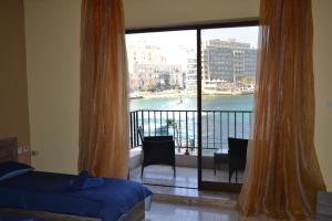 1 dormitorio con balcón con vistas al agua en Le Malte House St. Julians en San Julián