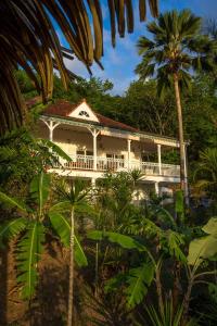 biały dom z gankiem i palmami w obiekcie Carre Royal w mieście Deshaies