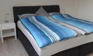 uma cama com um cobertor azul e branco em Ferienwohnung Kerstenhof em Willich