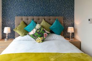 a bedroom with a large bed with green and blue pillows at Trumpington Townhouse with Parking and sleeps 6 - 5 mins to Papworth hospital in Cambridge