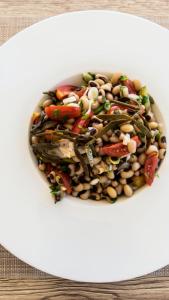 a bowl of beans and vegetables on a table at Mesogios Beach in Kissamos +34 photos
