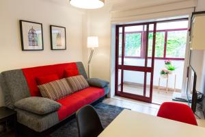 uma sala de estar com um sofá vermelho e uma porta de vidro deslizante em Casa Oliveira in Downtown Porto II em Porto