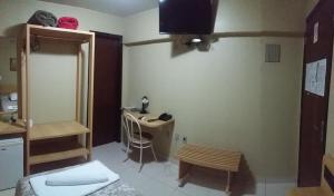 a small room with a desk and a room with a bed at Hotel Da Vila in Joinville