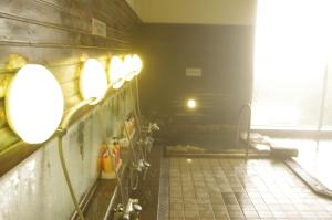 baño con luces en la pared y suelo de baldosa en Iwanai Kogen Hotel, en Iwanai
