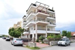 a white building with cars parked in front of it at Theoni's Seaside Apartment in Kalamata
