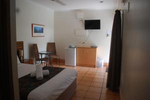 une chambre d'hôtel avec un lit, une table et des chaises dans l'établissement Rainforest Motel, à Mission Beach