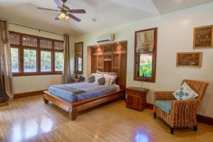 a bedroom with a bed and a chair and windows at Ho'oilo House in Lahaina